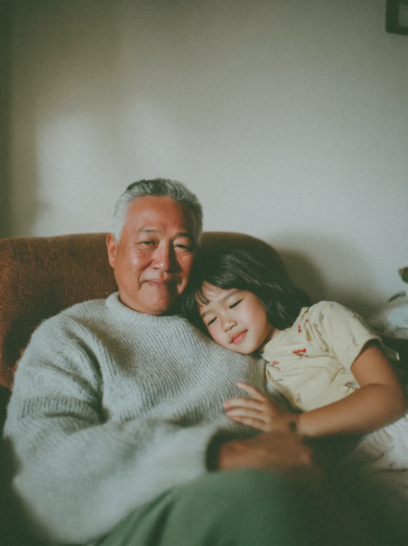 Older man sitting with a young child resting against him